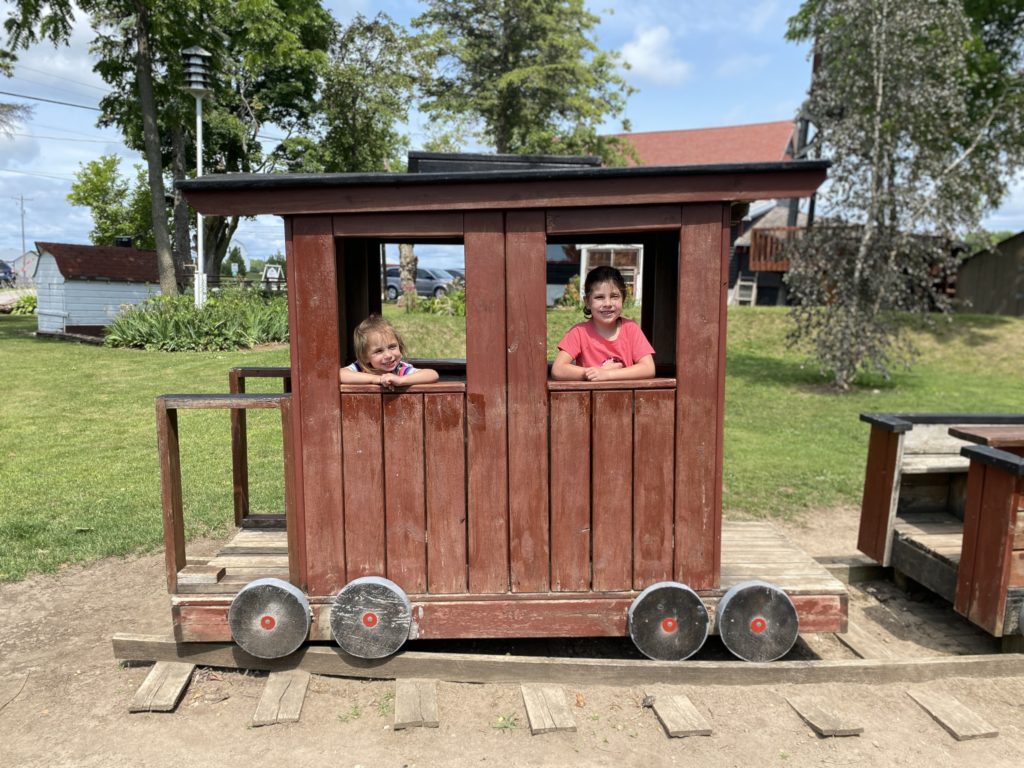 two girls outside in a wooden play train