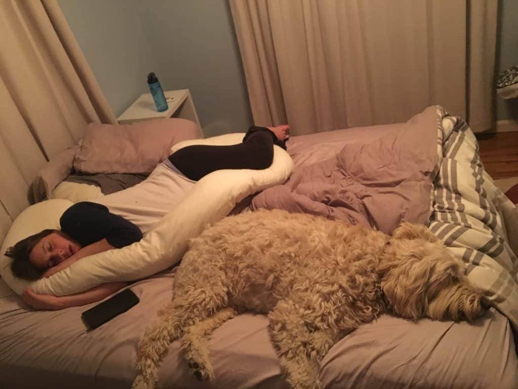 pregnant woman with body pillow on bed