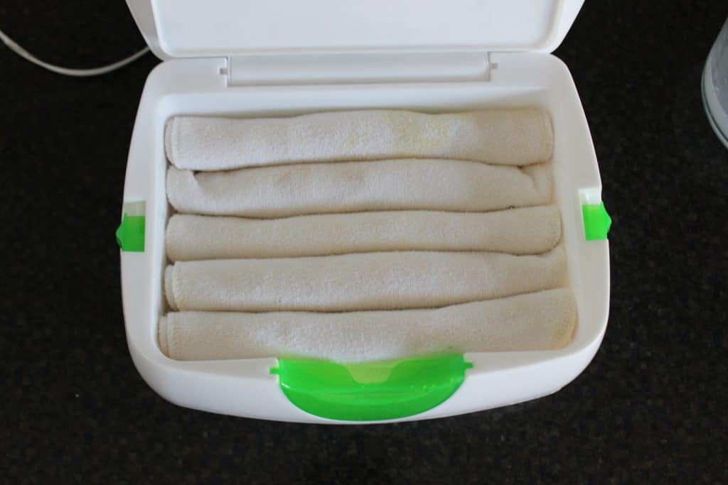 open wipe warmer with five wipes rolled up next to each other