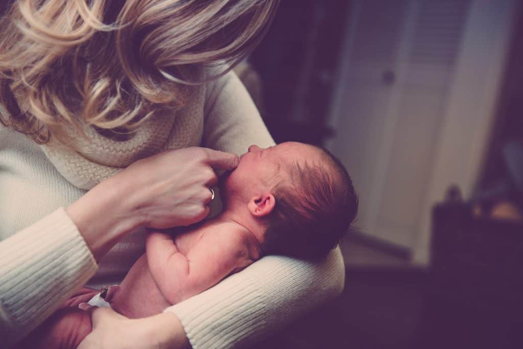 blonde woman holding newborn in arms