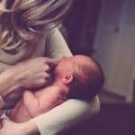blonde woman holding newborn in arms