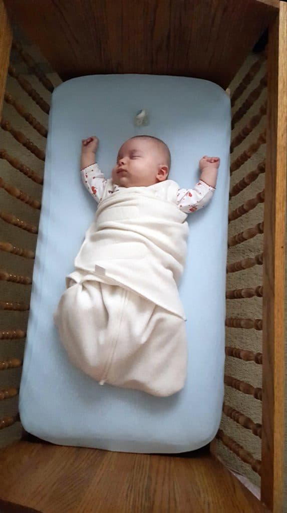 swaddled baby sleeping in cradle