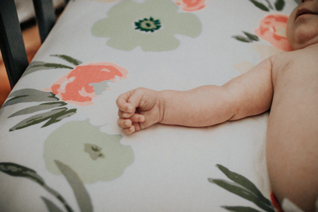 close-up of baby laying in crib with a floral sheet