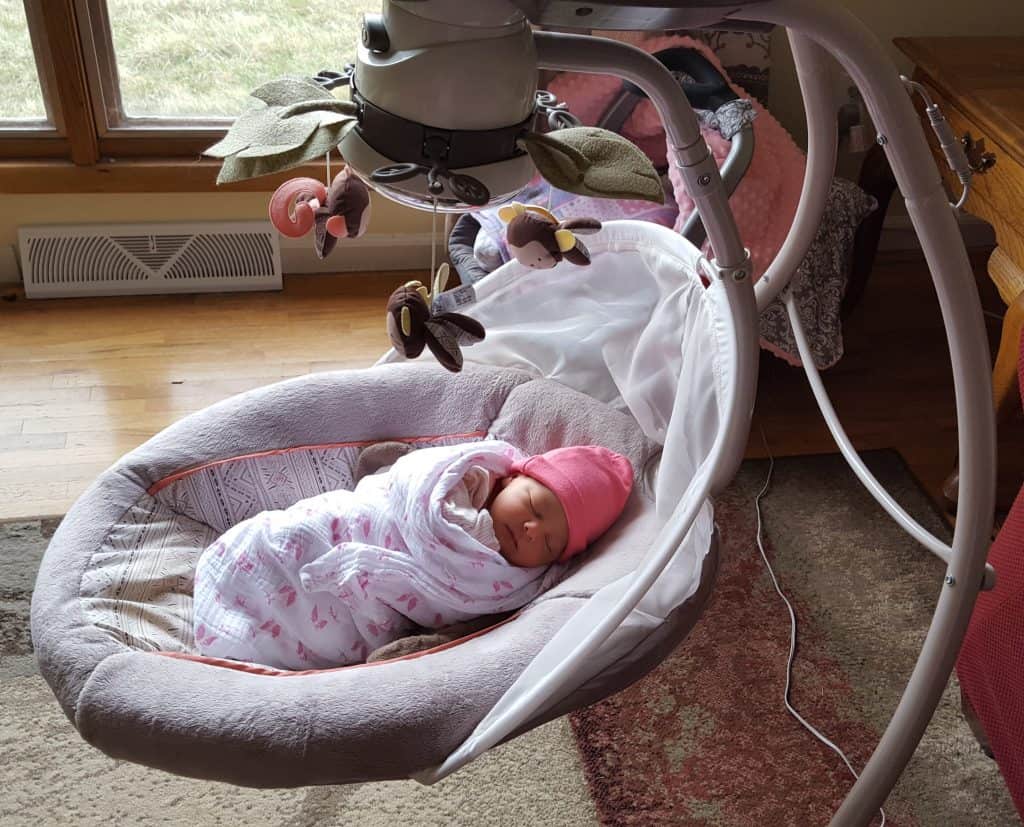 swaddled baby laying in baby swing