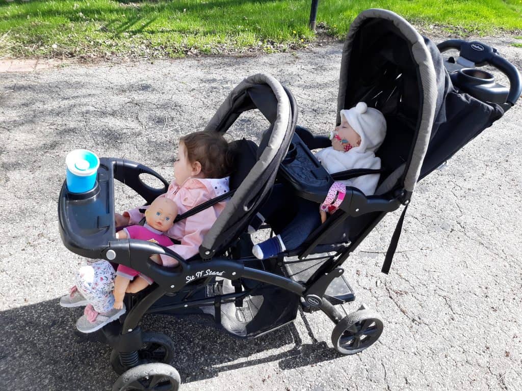 two toddlers sleeping in a double stroller