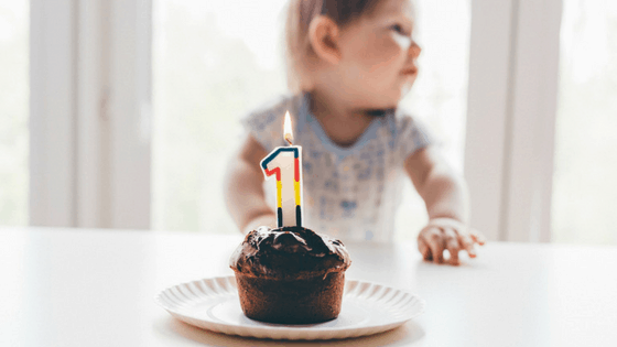 one year old with a chocolate cupcake and the number one birthday candle