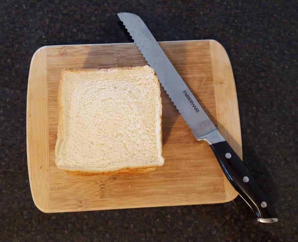 slice of Texas toast and serrated knife on wooden cutting board