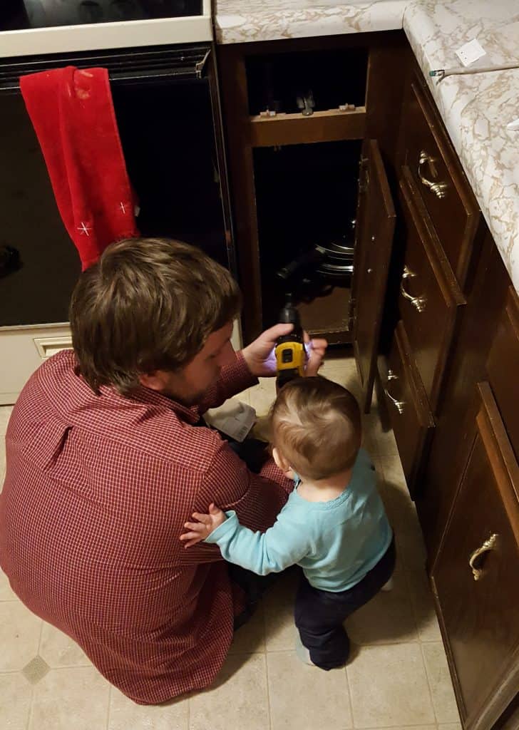 Dad and baby baby-proofing cabinets