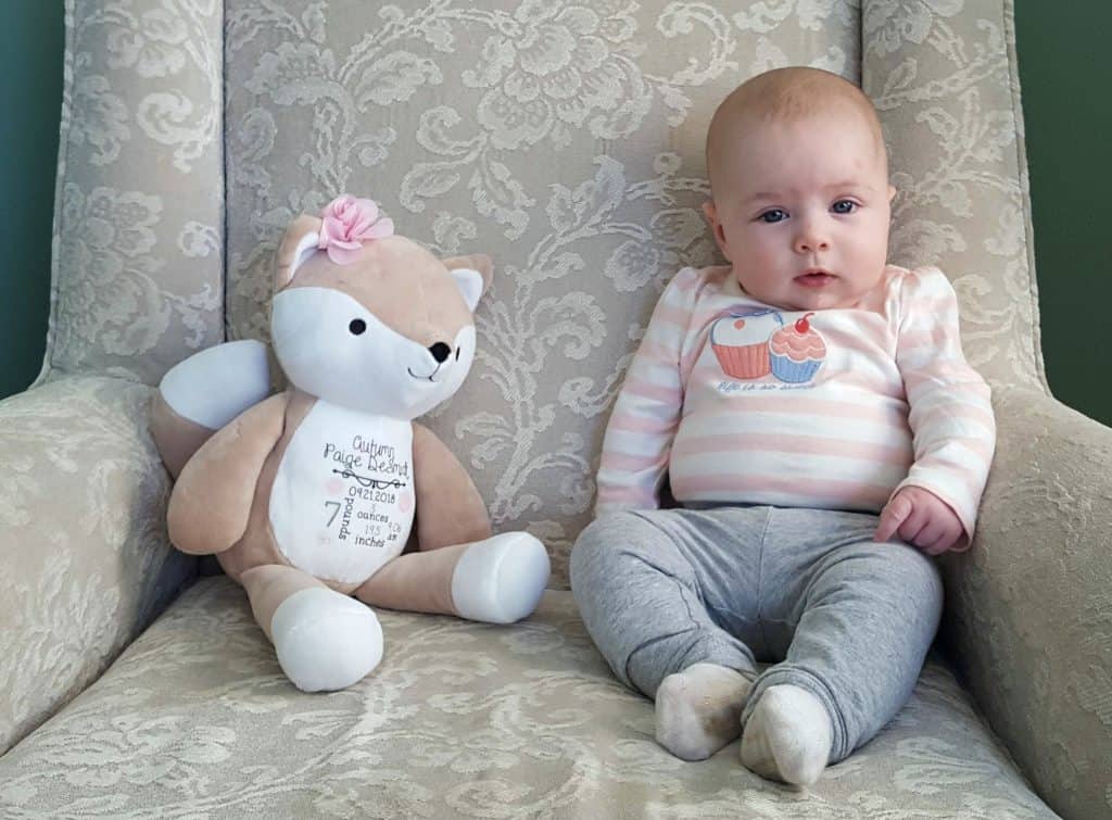 baby seated in chair next to stuffed animal