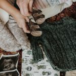 posed photo of ultrasound, gray baby sweater, and brown baby sandals