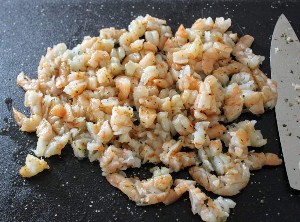 chopped up cooked shrimp on black cutting board