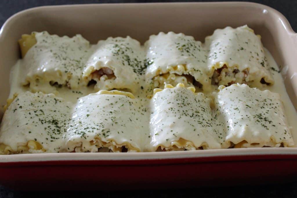 red pan with eight lasagna roll ups topped with alfredo sauce