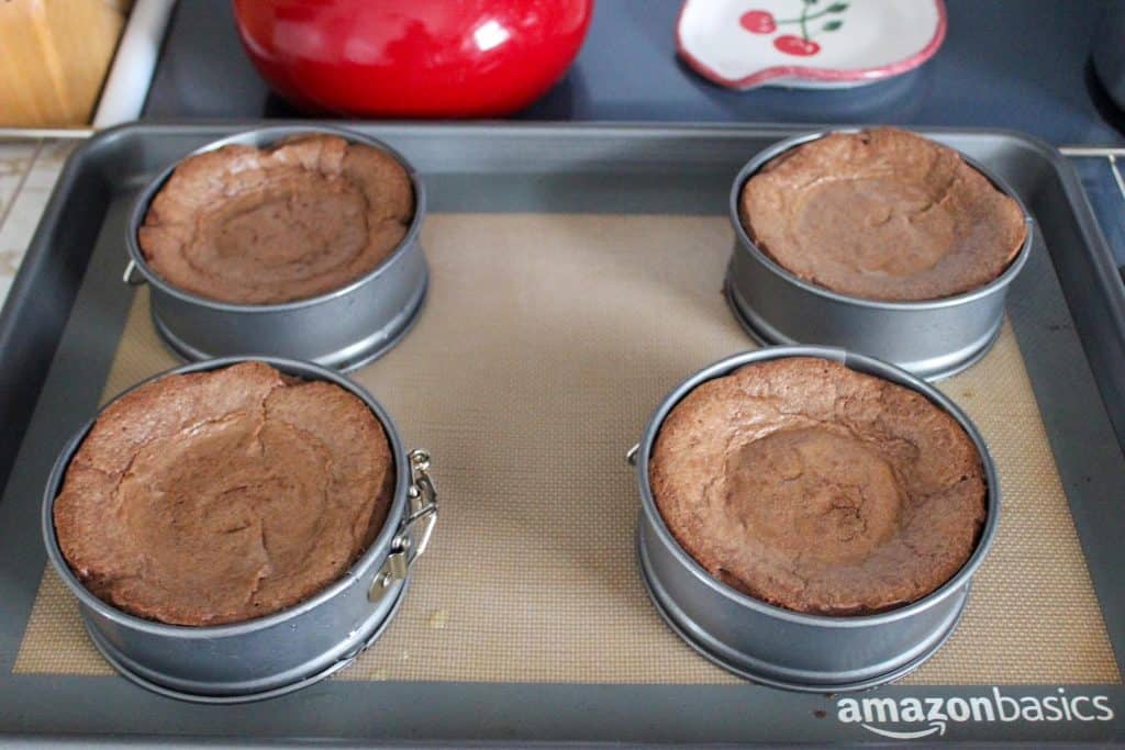 four baked flourless chocolate cakes on a pan with silicone baking mat