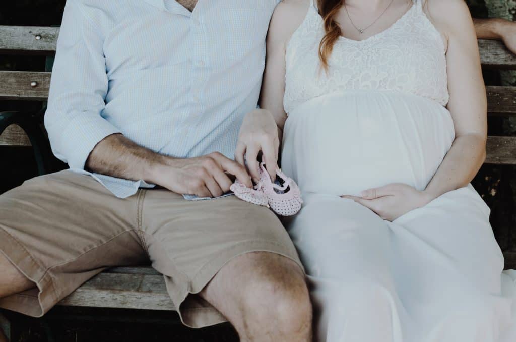 parents-to-be holding baby shoes