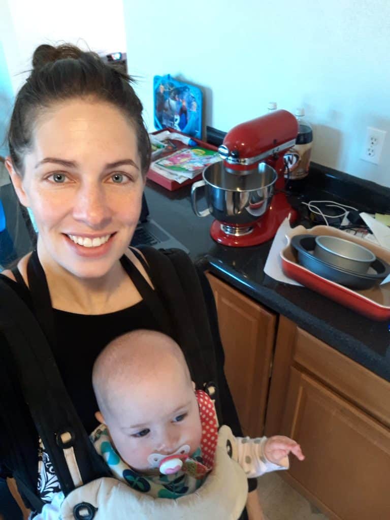 mom (author) carrying baby in front carrier with stand mixer in background