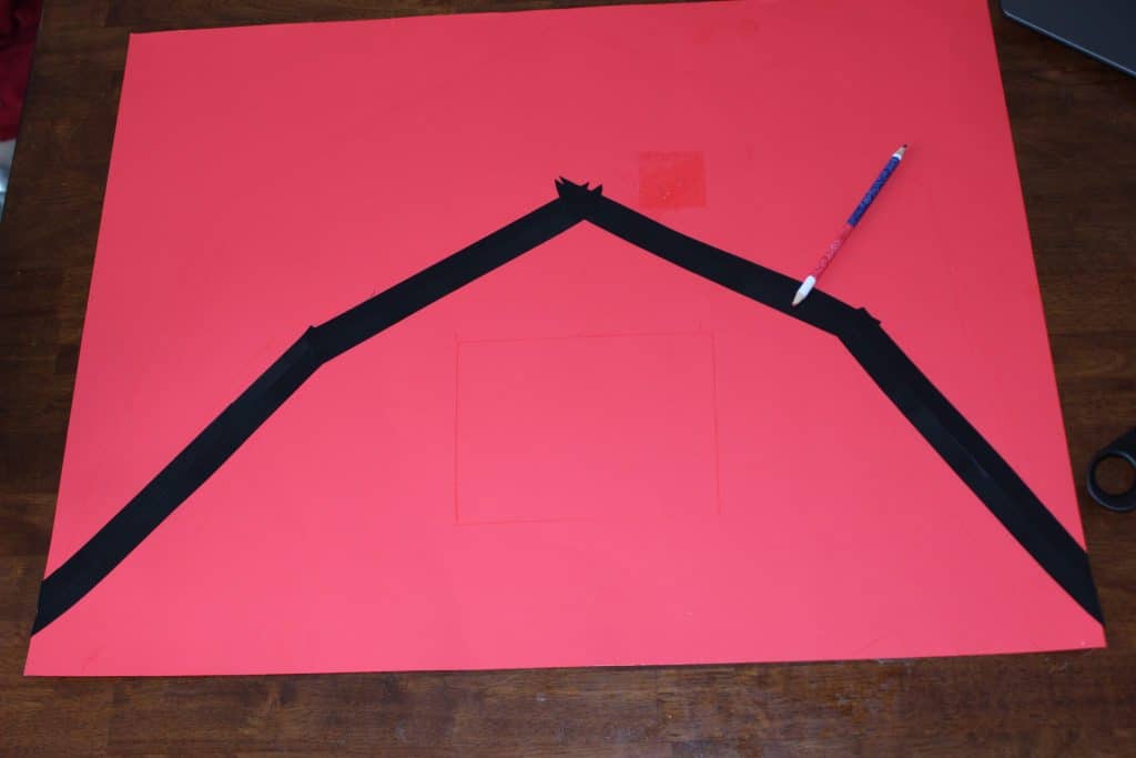black electrical tape on red posterboard outlining the barn roof