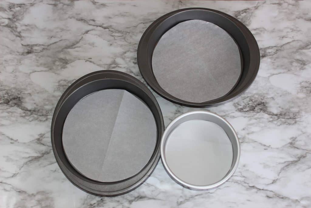 two large and one small round cake pans with parchment bottoms