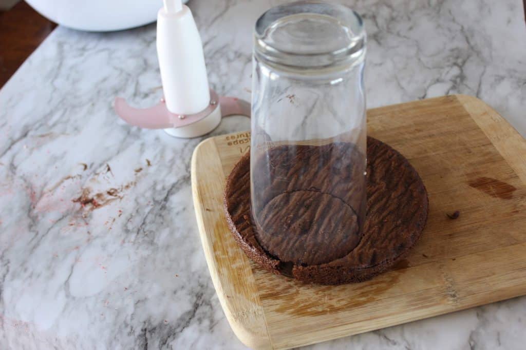 small round chocolate cake with a tall water glass cutting a round circle