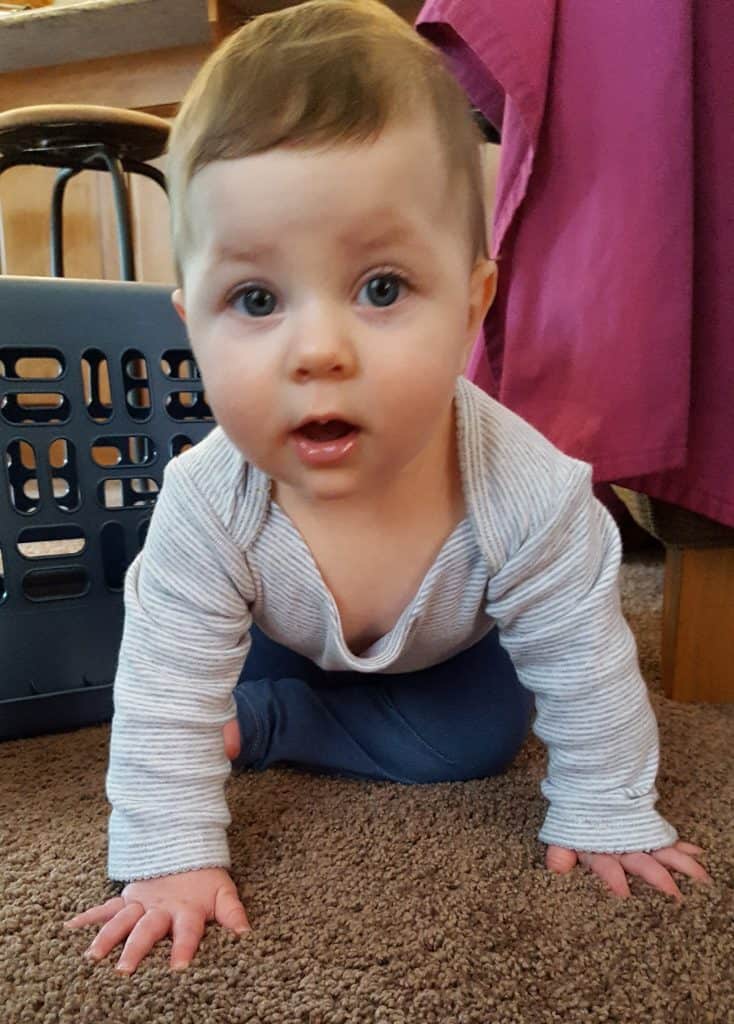 baby in gray long-sleeve onesie and denium pants