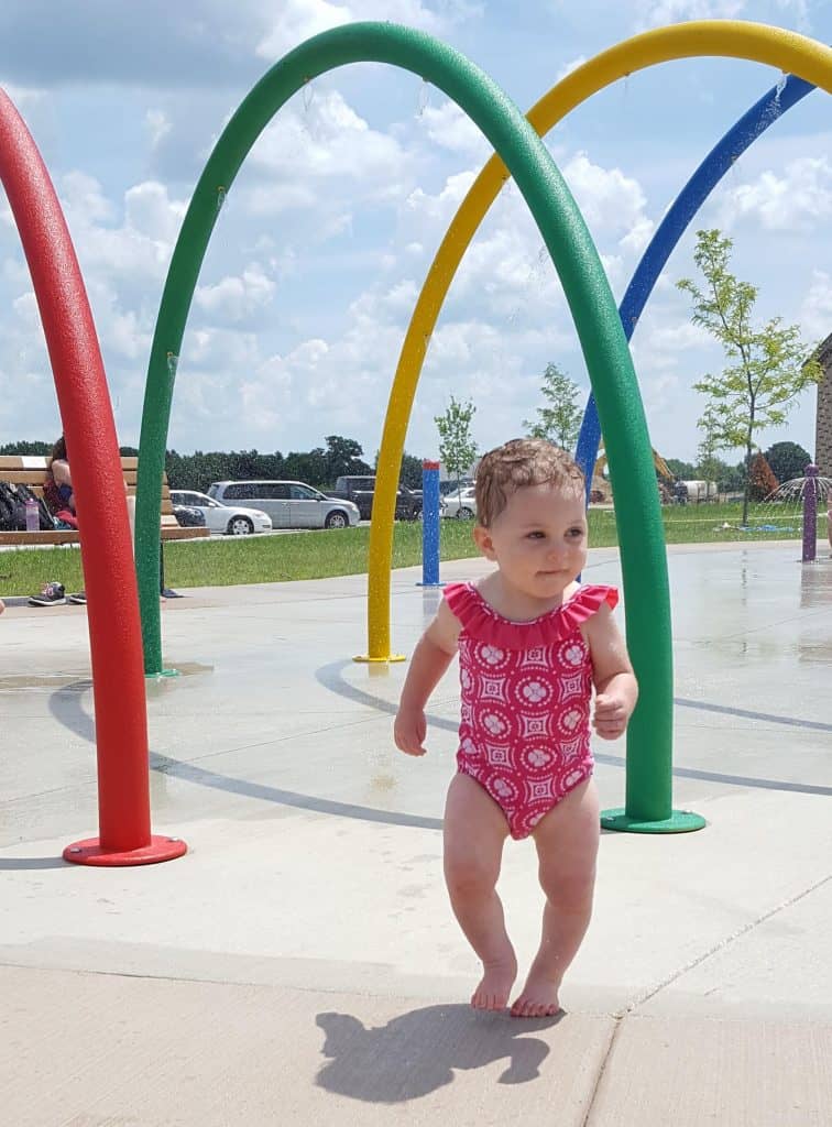 toddler running through a splashpad