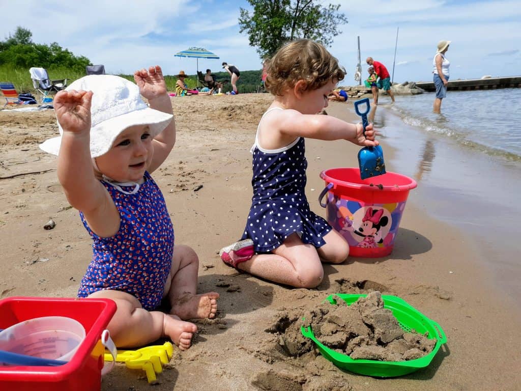 baby and toddler playing in sand at the beach