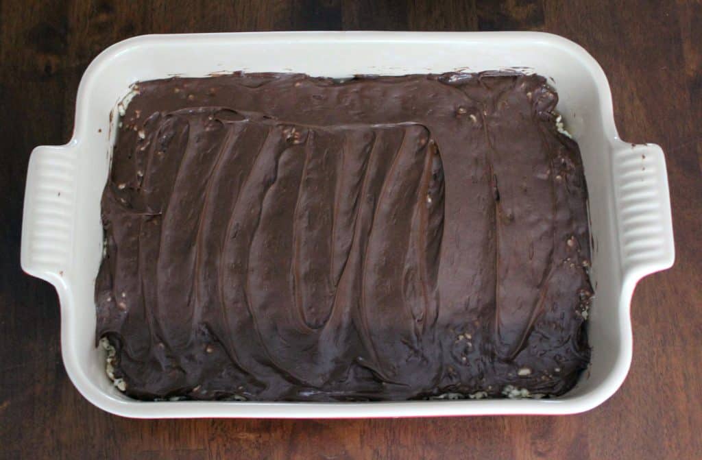 rice krispie treats in pan with chocolate frosting spread on top