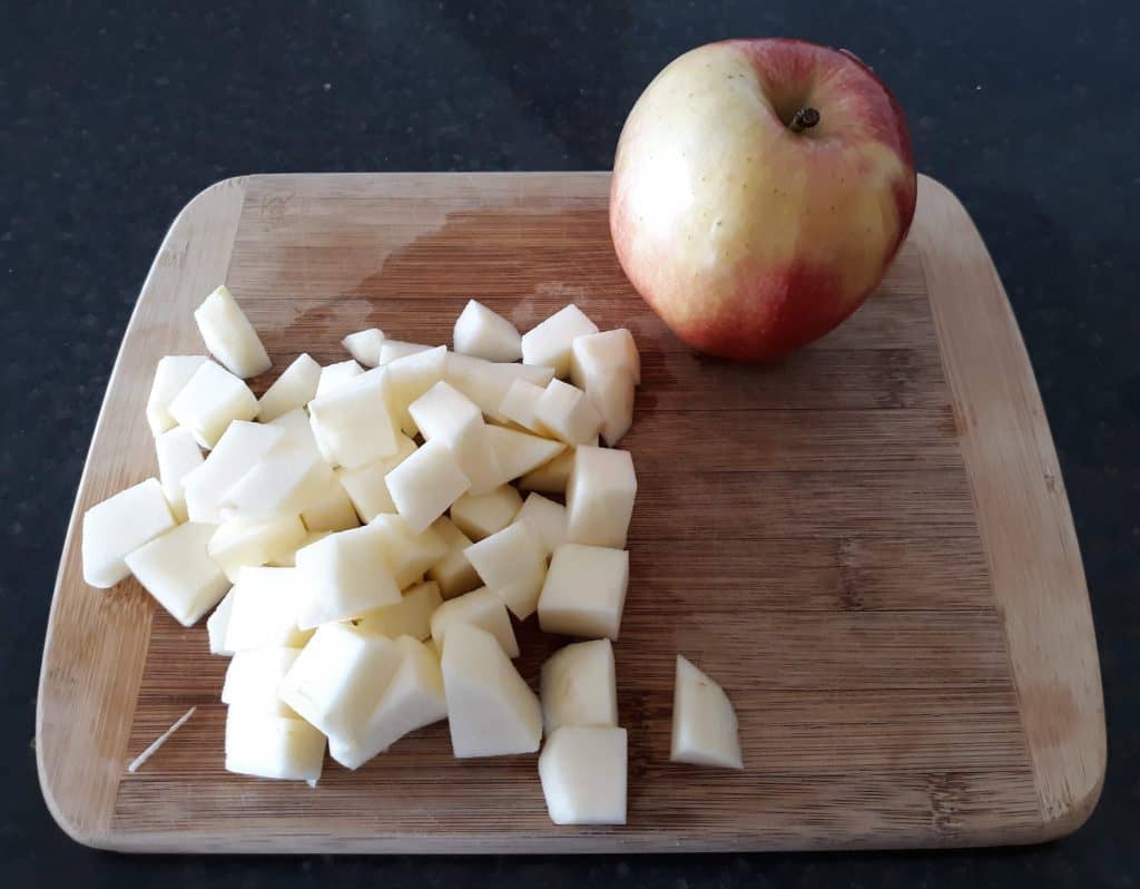 diced apple on cutting board with a whole apple