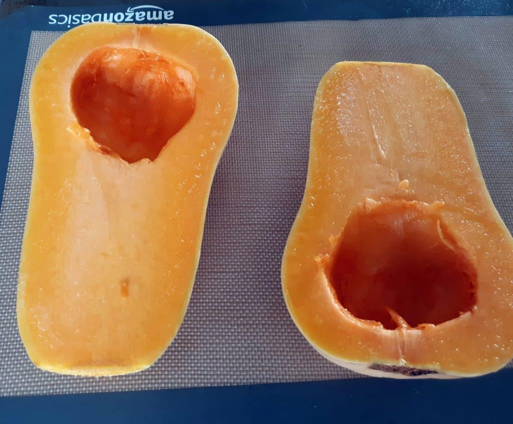 butternut squash sliced in half on baking sheet