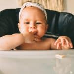 baby in high chair with fingers in mouth