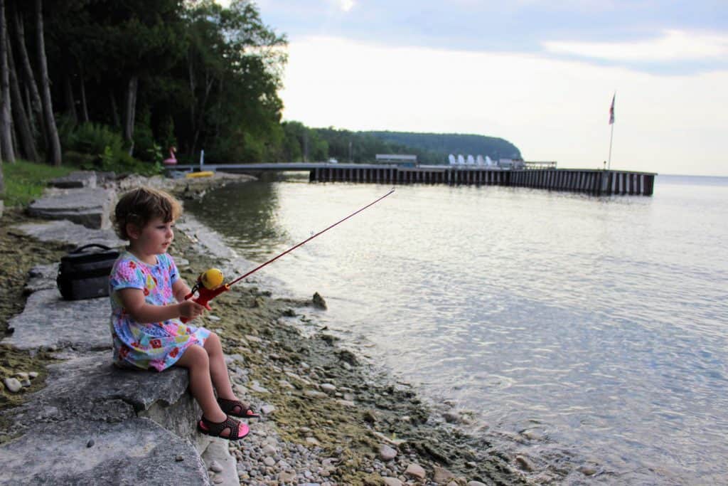 toddler sitting on rocks fishing