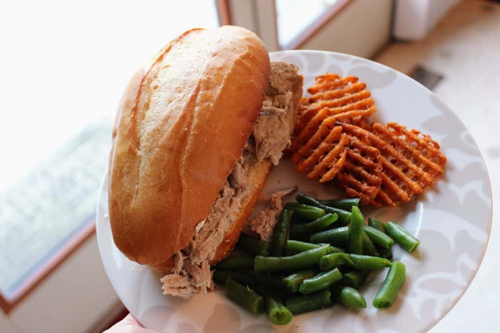 French dip sandwich on plate with sweet potato fries and green beans