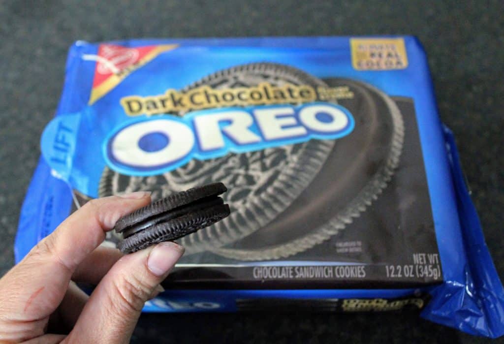 Dark Chocolate Oreo held between two fingers in front of packaging