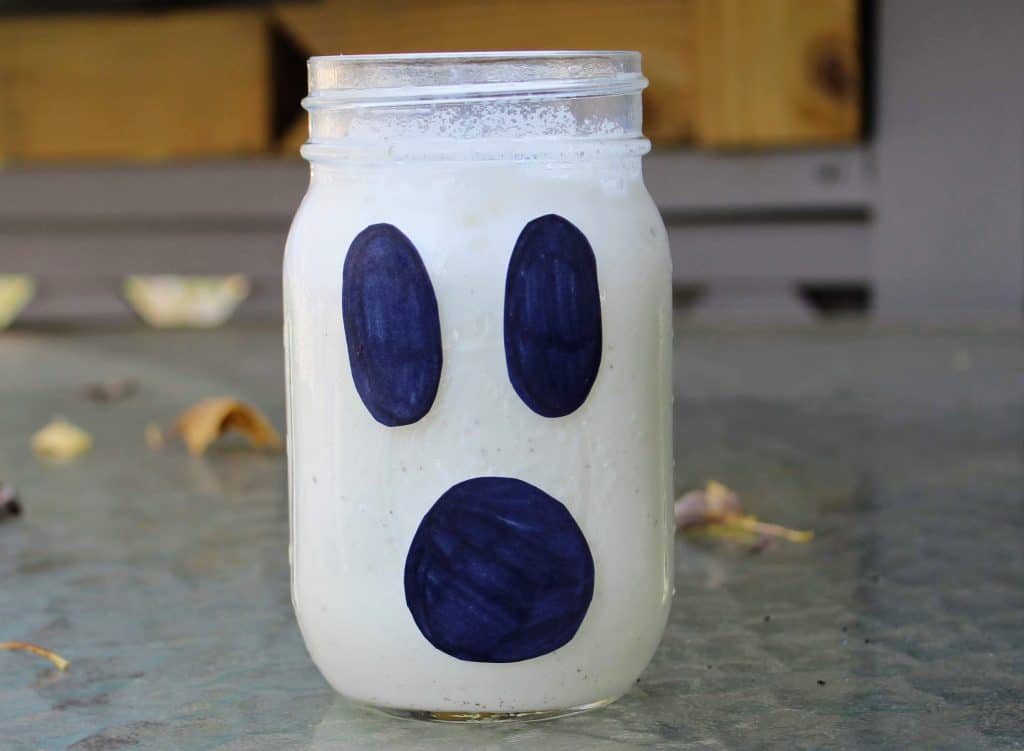 mason jar filled with vanilla ice cream with black paper glued on to make a ghost face