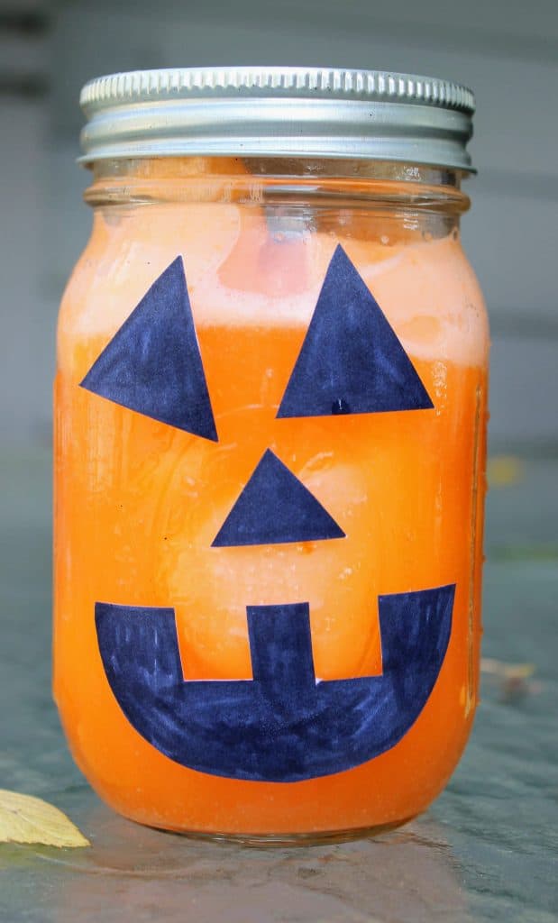 orange sherbet and orange soda in a mason jar with black pieces of paper making a carved pumpkin face