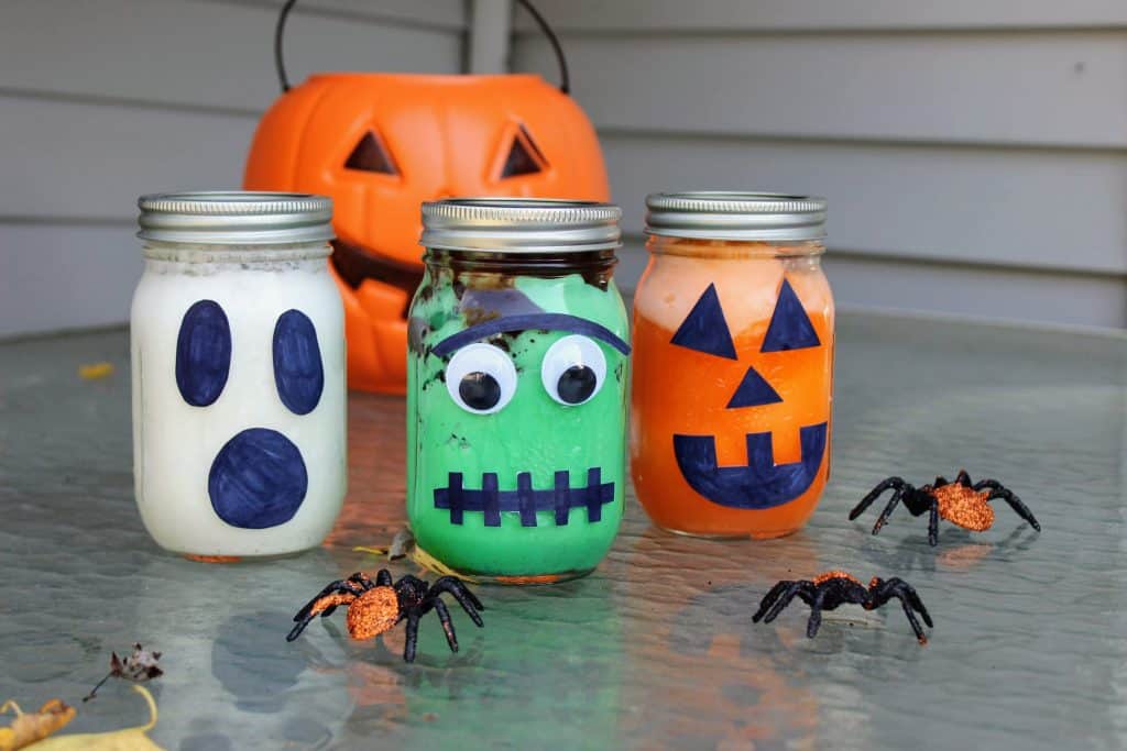 mason jars filled decorated to look like a pumpkin, ghost, and Frankenstein's monster filled with ice cream