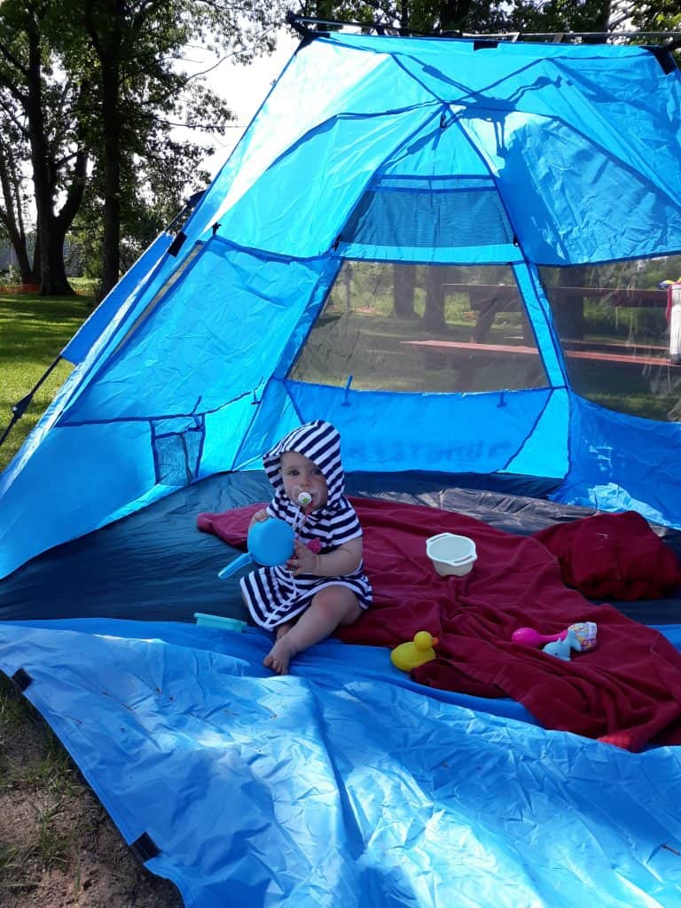 baby sitting in sun tent