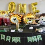 Wild One balloons and jungle animal balloons behind beverage and cake table