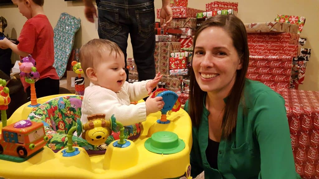 baby in exersaucer with Christmas presents in background
