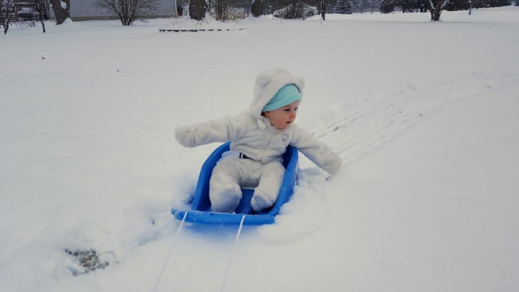 baby in snowsuit sledding