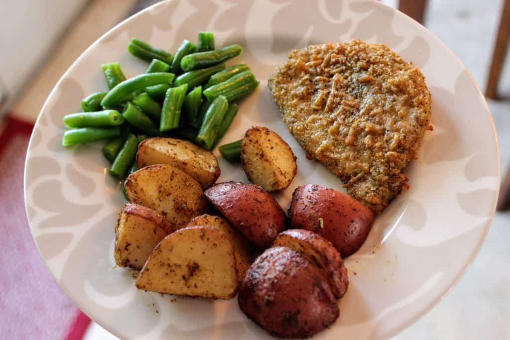 dinner plate with pork chop, red potatoes, and green beans