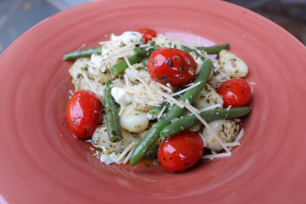 red bowl of gnocchi, green beans, and grape tomatoes