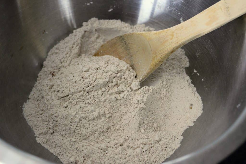 dry ingredients mixed together in a mixing bowl with wooden spoon