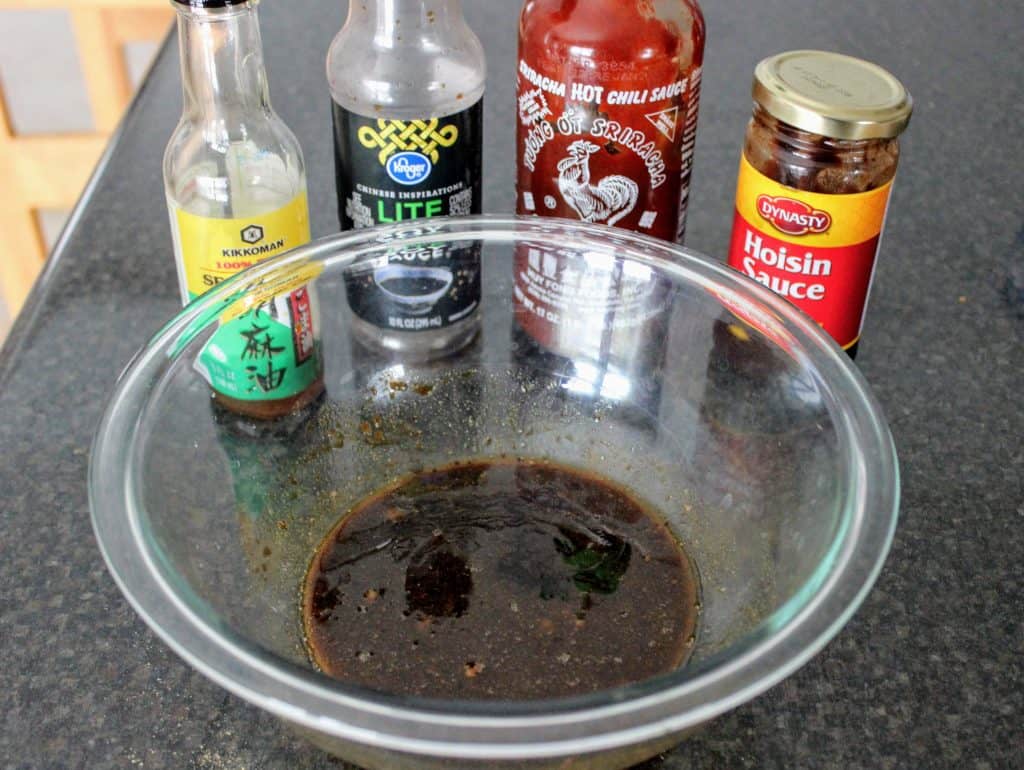 bowl of sauce ingredients with bottles behind the bowl