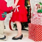 children dressed up for Christmas standing next to presents
