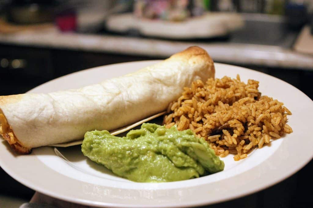 chicken taquito, rice, and guacamole on a plate