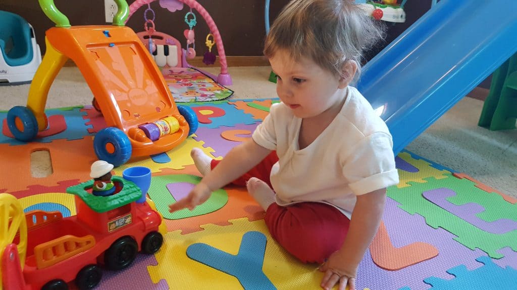 toddler sitting on floor playing with toys