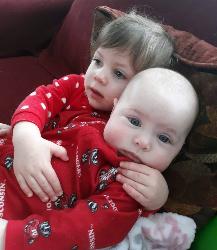 toddler with arms around baby