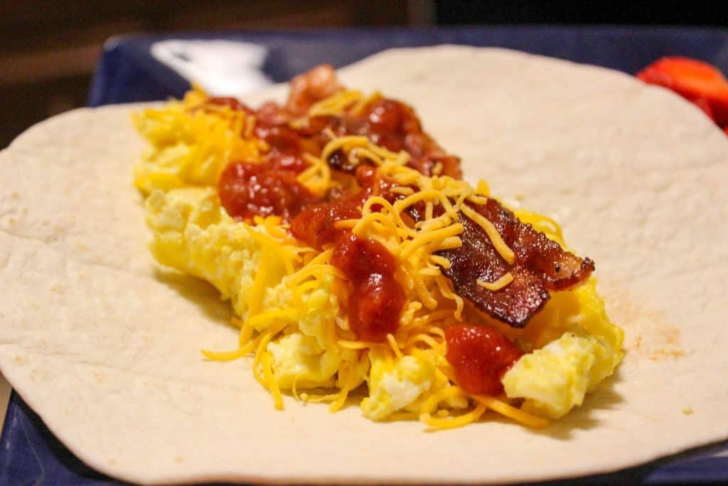 tortilla filled with scrambled eggs, cheddar cheese, bacon, and salsa