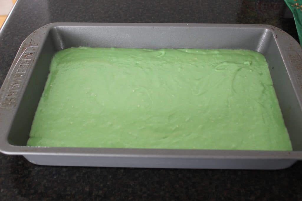 green cake batter in a 9x13 pan