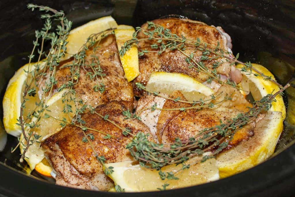 chicken thighs in slow cooker with lemon wedges and herbs